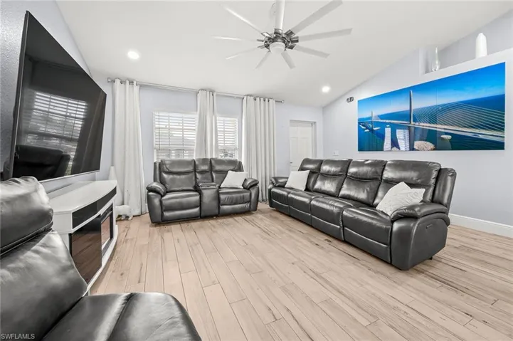 Living area featuring light wood-style flooring, vaulted ceiling, a ceiling fan, and recessed lighting