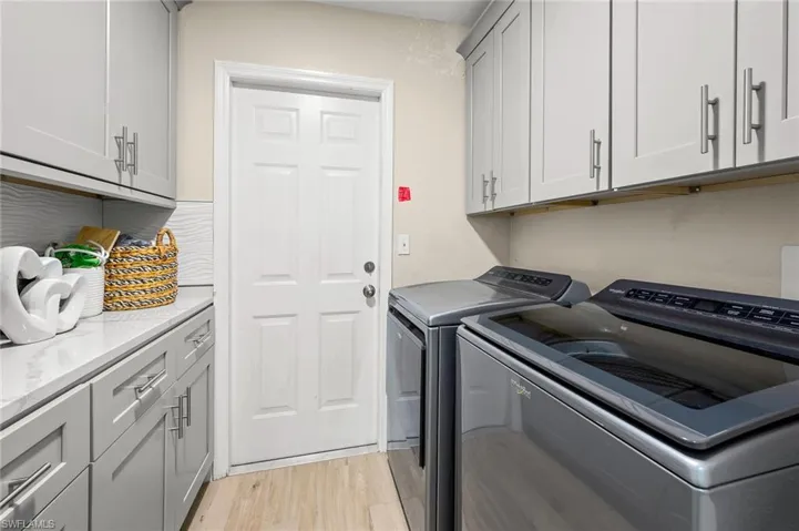 Laundry area featuring cabinet space, light wood-style floors, and washer and dryer