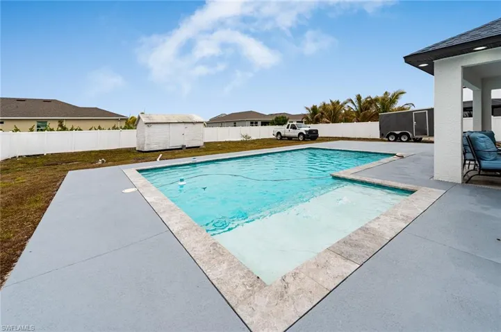 View of swimming pool featuring patio surround, a storage shed, and a fenced backyard
