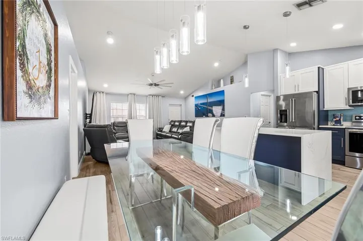 Dining area featuring ceiling fan, wood tiled floors, vaulted ceiling, and recessed lighting