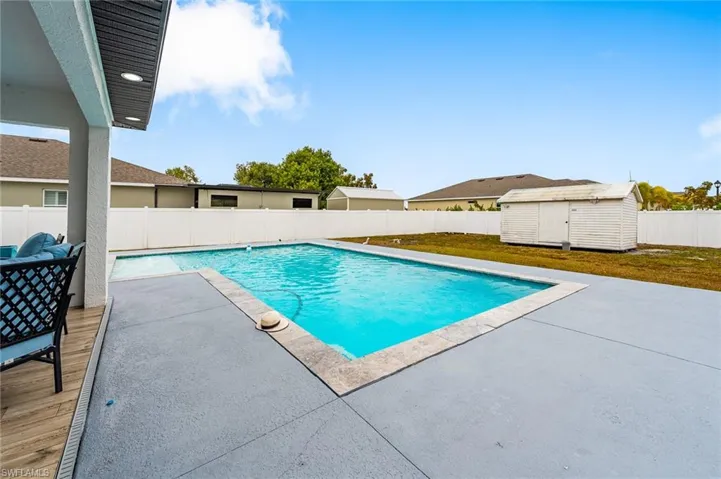 View of swimming pool featuring patio surround, a fenced backyard, and a storage unit