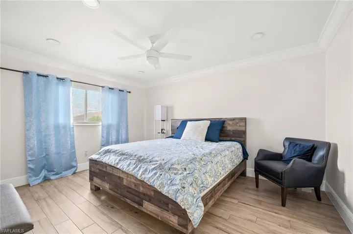 Bedroom featuring ornamental molding, light wood finished floors, and ceiling fan