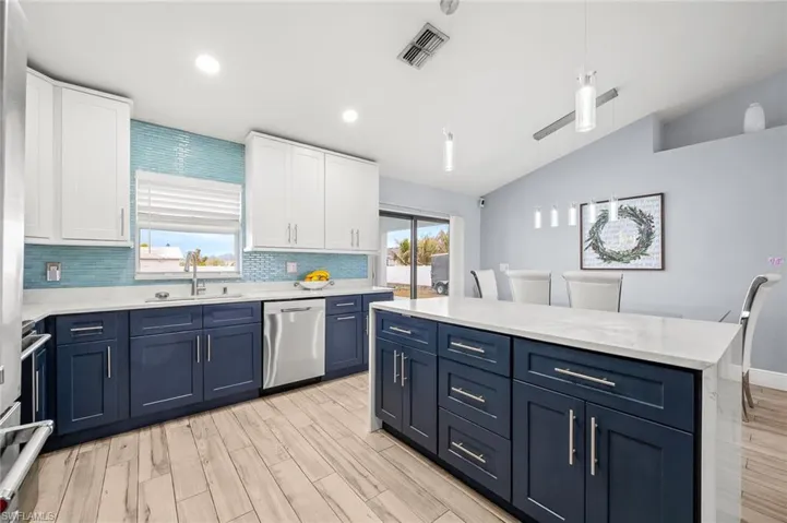 Two tone kitchen featuring two tone color scheme, backsplash, dishwasher, light wood-style flooring, and a kitchen island