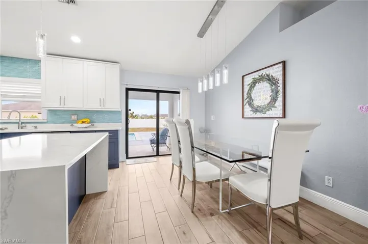 Dining area with wood tiled floors, vaulted ceiling, and recessed lighting