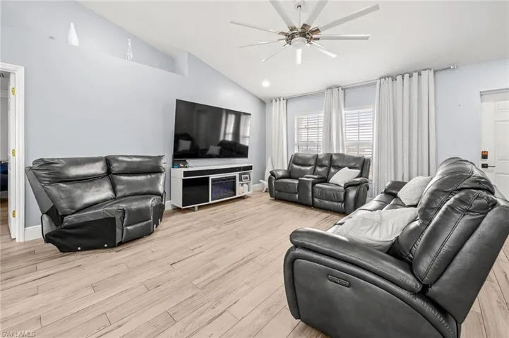 Living room with light wood finished floors, a ceiling fan, and lofted ceiling