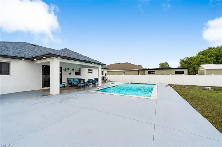 View of pool with patio surround, a fenced backyard, and outdoor seating