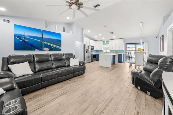 Living room with a ceiling fan, vaulted ceiling, light wood-style floors, and recessed lighting