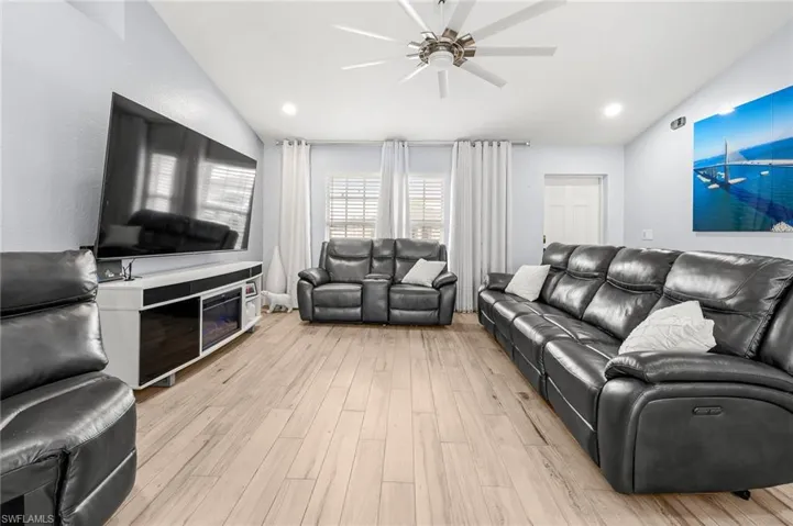 Living room with light wood-style floors, ceiling fan, and recessed lighting