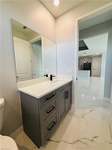 Bathroom, baseboards, toilet, porcelain finish floor, and vanity