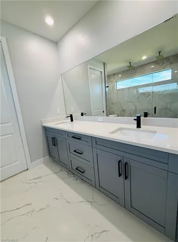 Full bath featuring double vanity, a stall shower, porcelain finish floor, and a sink