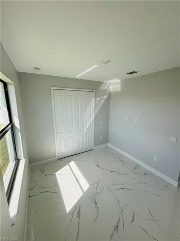 Unfurnished bedroom featuring porcelain finish floor, visible vents, and baseboards