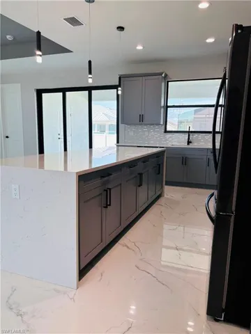 Kitchen featuring a kitchen island, visible vents, porcelain finish floor, freestanding refrigerator, and pendant lighting