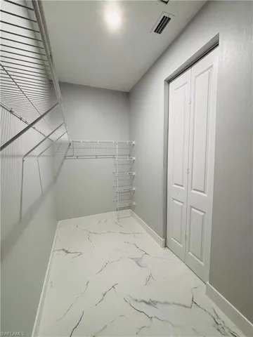 Spacious closet with porcelain finish floor and visible vents