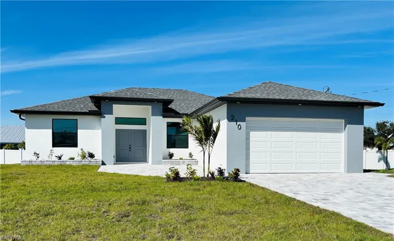 View of front facade featuring a garage, decorative driveway, a front yard, and stucco siding