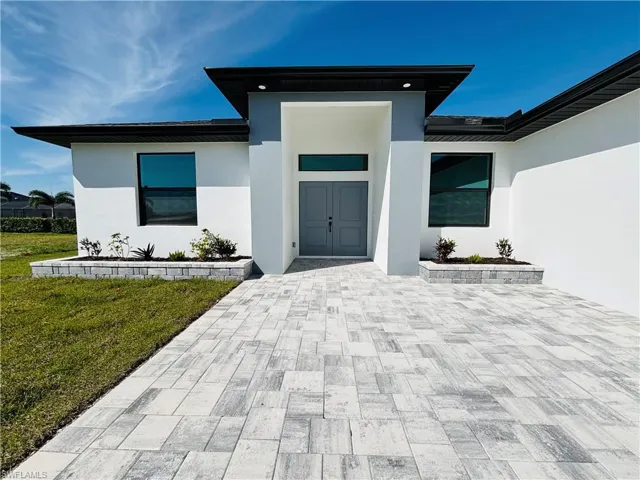 View of exterior entry featuring a lawn and stucco siding