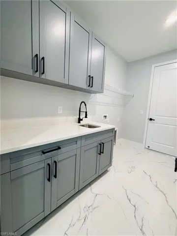 Washroom with hookup for a washing machine, cabinet space, porcelain finish floor, and a sink
