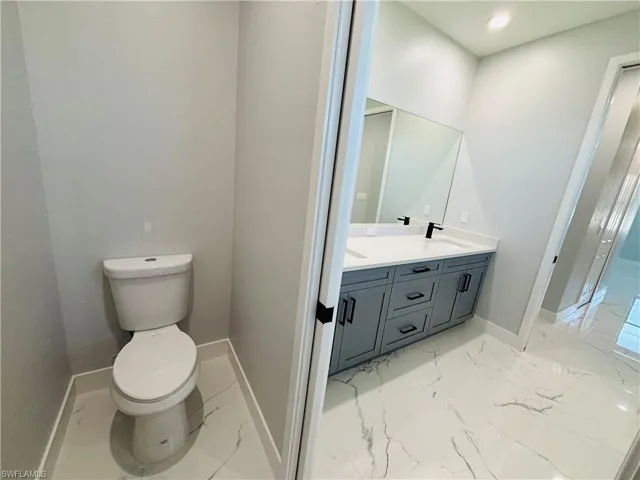 Full bath with porcelain finish floor, baseboards, a sink, and toilet