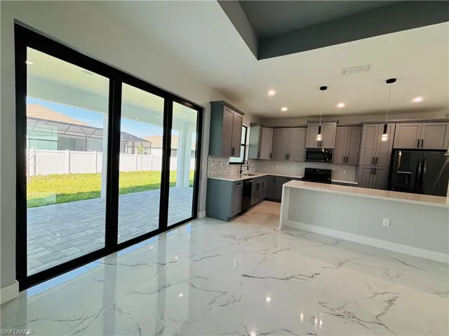 Kitchen featuring gray cabinetry, light countertops, decorative backsplash, black appliances, and decorative light fixtures