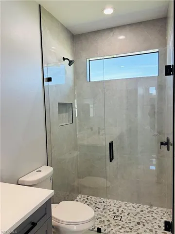Full bathroom featuring toilet, a stall shower, and vanity