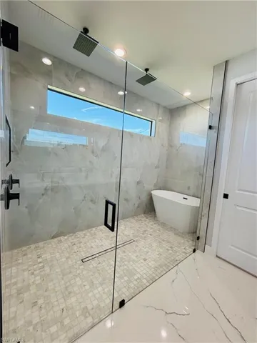 Full bath with porcelain finish floor, a soaking tub, a marble finish shower, and recessed lighting