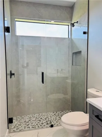 Bathroom with toilet, a stall shower, and vanity