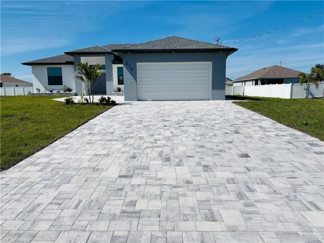 Prairie-style home with decorative driveway, a front yard