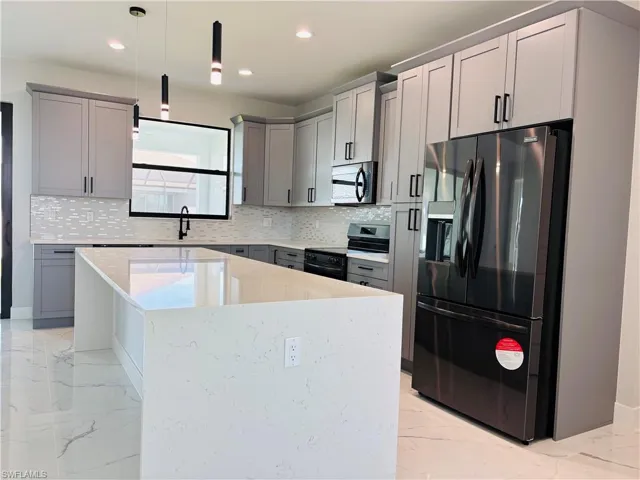 Kitchen with porcelain finish floor, appliances with stainless steel finishes, a kitchen island, and hanging light fixtures