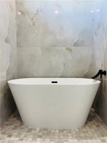 Full bathroom featuring a soaking tub and tile walls