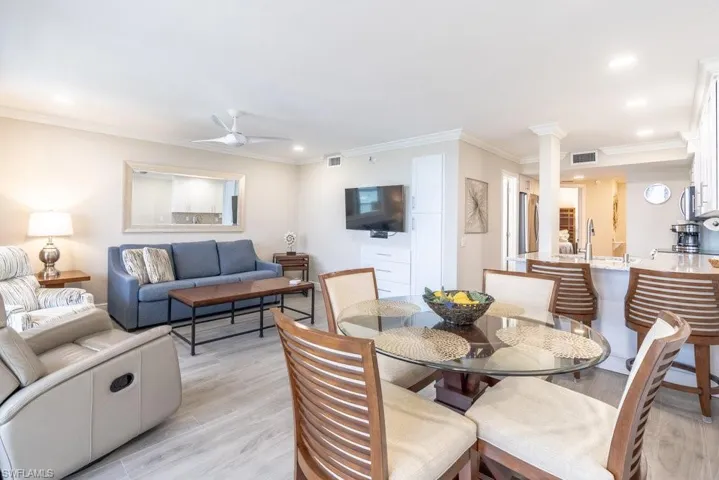 Dining room featuring light wood finished floors, a ceiling fan, ornamental molding, recessed lighting, and decorative columns