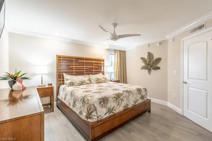 Bedroom featuring crown molding, light wood-type flooring, and a ceiling fan