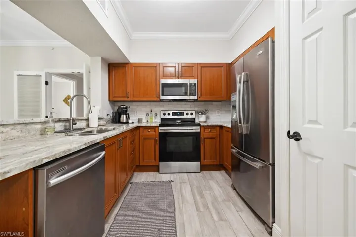 Kitchen with SS appliances, light stone countertops,tile backsplash