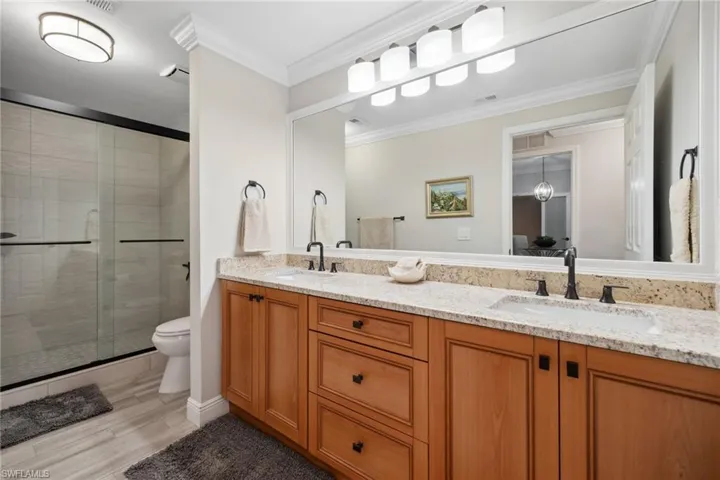 Full bathroom featuring double vanity with light granite countertops, and large walk-in shower