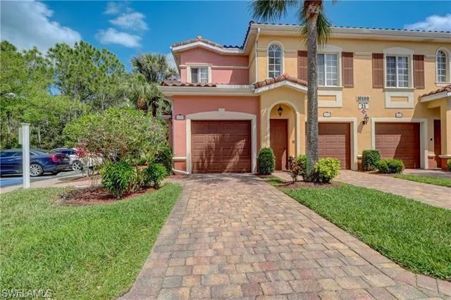View of front of house featuring an attached garage, driveway, and tiled roof