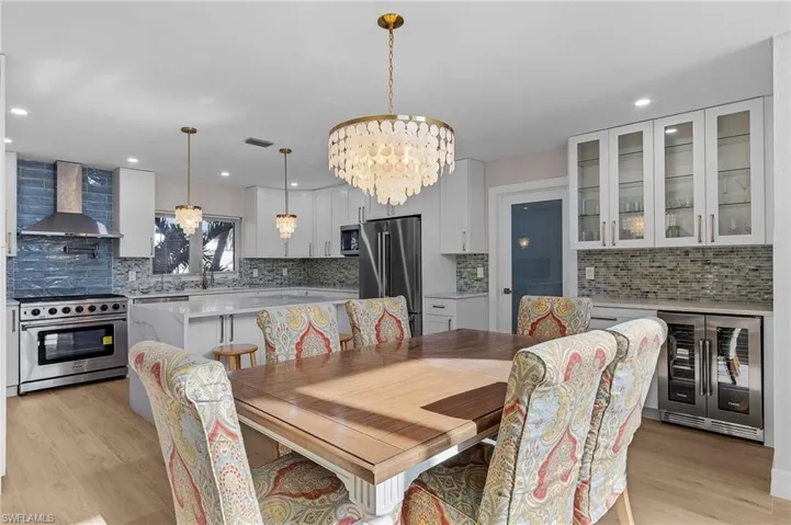 Dining room featuring wine cooler, a chandelier, light wood-style flooring, and recessed lighting