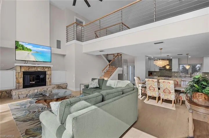 Living area with a fireplace, stairs, wood finished floors, and ceiling fan