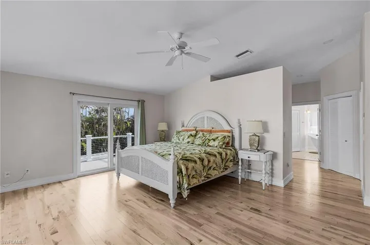 Bedroom with access to exterior, light wood-style flooring, a ceiling fan, and vaulted ceiling