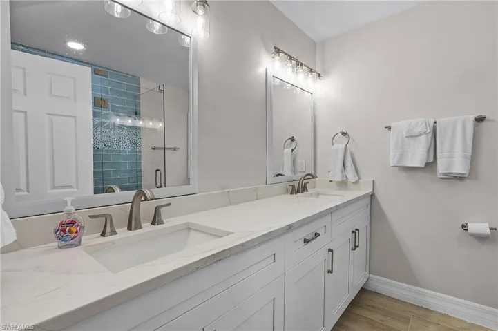 Bathroom with a stall shower, double vanity, and light wood-style floors