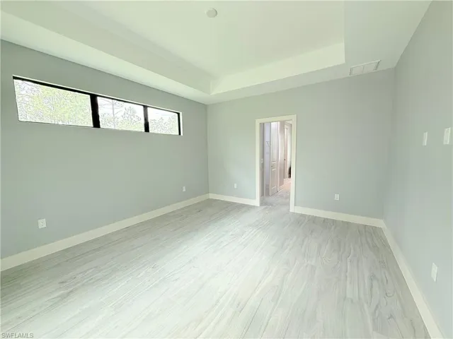 Unfurnished room with light hardwood / wood-style flooring and a tray ceiling