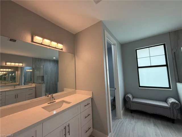 Bathroom featuring toilet, walk in shower, and vanity