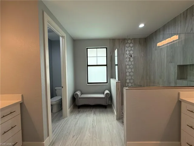 Bathroom with toilet, a shower, wood-type flooring, and vanity