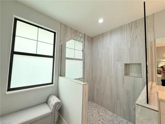 Bathroom featuring a healthy amount of sunlight, tiled shower, and vanity