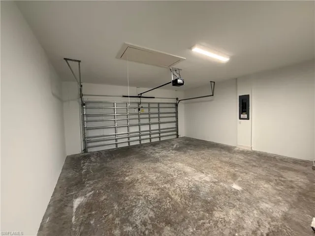 Garage featuring a garage door opener and electric panel