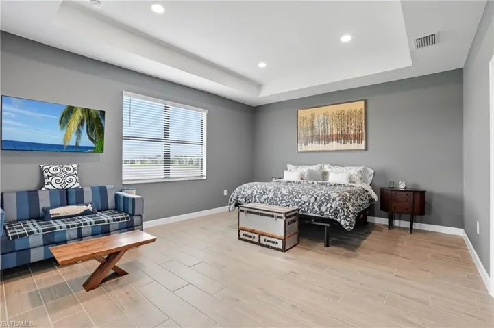 Bedroom with a raised ceiling, wood tiled floors, and recessed lighting
