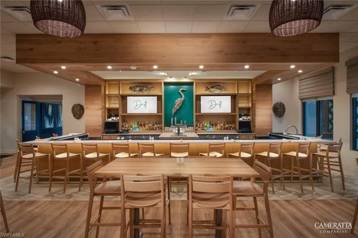 Bar area with light wood-style floors, open shelves, recessed lighting, and a drop ceiling