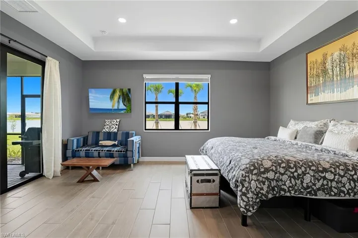 Bedroom featuring wood finished floors, a raised ceiling, access to outside, and recessed lighting