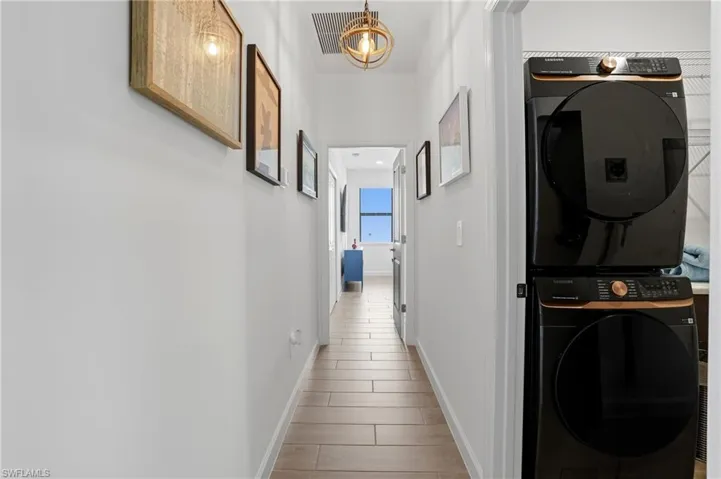 Corridor with stacked washer / drying machine and wood tiled floors
