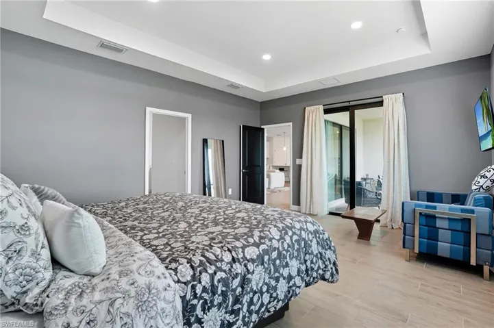 Bedroom with a tray ceiling, light wood-type flooring, and recessed lighting