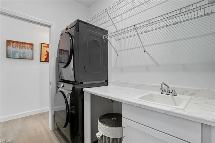 Laundry area featuring light wood finished floors and stacked washing machine and dryer