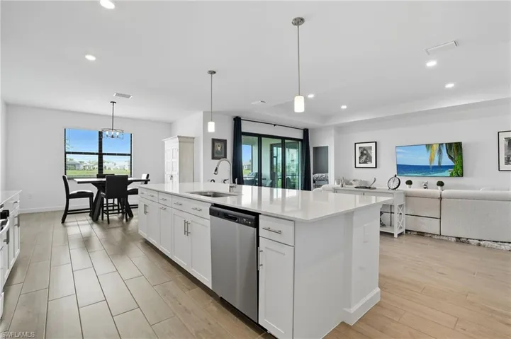 Kitchen with hanging light fixtures, white cabinetry, recessed lighting, and open floor plan