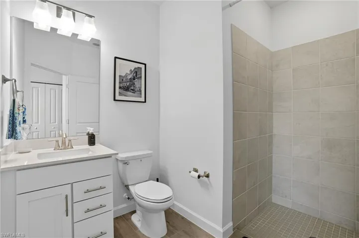 Full bathroom featuring vanity, light wood-style floors, and a tile shower